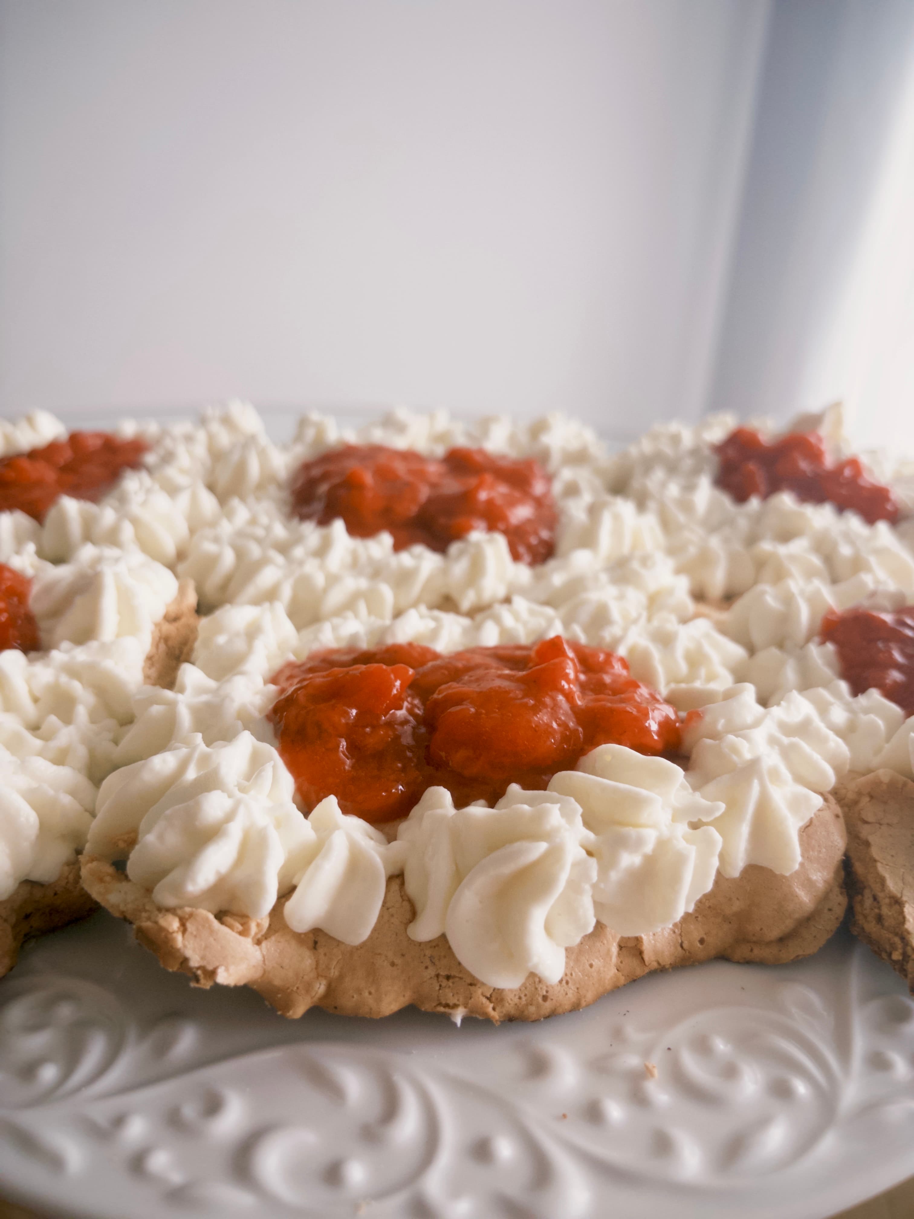 Danish-shaped Pavlova topped with cream and raspberries